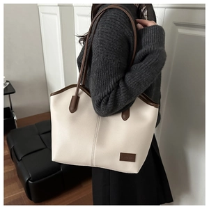 Detail showing the creamy white lychee leather texture and brown strap of the tote bag