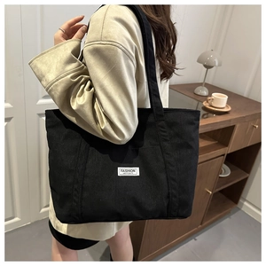 Detailed texture of black corduroy tote bag with Fashion Instinct label and reinforced handle