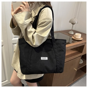 Detailed texture of black corduroy tote bag featuring a stitched Fashion Instinct label