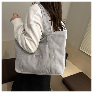 Close-up of light gray corduroy tote bag showing side pocket and Fashion Instinct label