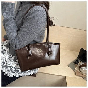 Detailed shoulder view of a dark brown glossy leather tote bag with knotted handles