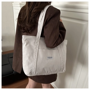 Detail of white corduroy tote bag featuring a Fashion Instinct label and soft texture