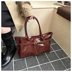 Chic reddish-brown tote bag with decorative buckle shown in a lifestyle street setting