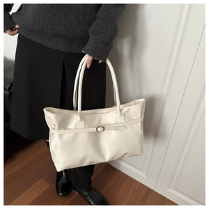 Close-up of minimalist cream-white shoulder bag featuring elegant buckle strap and leather texture