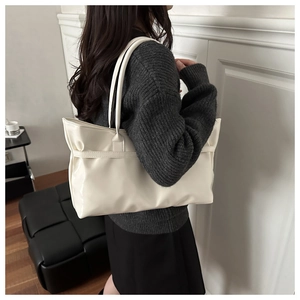 Detail view of large cream leather tote bag with strap accents for daily commuting