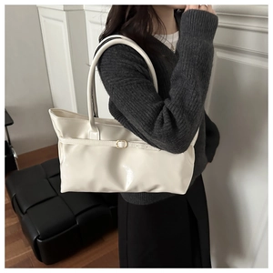 Minimalist beige shoulder bag with slim belt buckle shown as model side-wear style