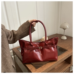 Macro detail of glossy dark red patent leather bucket bag with elegant buckle strap