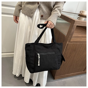 Détail du sac cabas en velours côtelé noir avec poche zippée et tirette en corde blanche