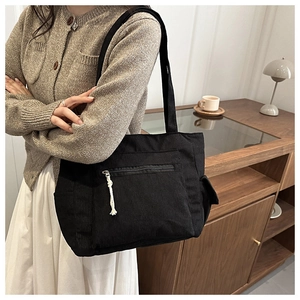 Détail du sac cabas en velours côtelé noir montrant la texture et la poche à cordon blanc