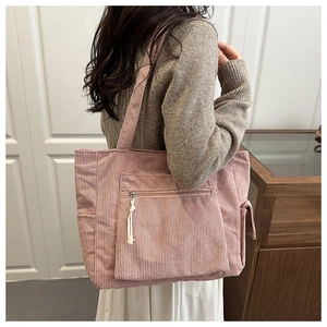 Détail latéral d'un sac cabas en velours côtelé rose avec poche et fermeture éclair