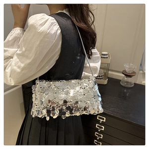 Silver sequin shoulder bag on model with metallic finish and delicate chain strap