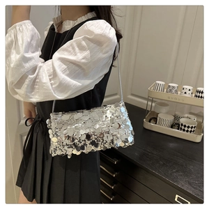 Borsa a spalla con paillettes argento e catena sottile indossata da modella in casa