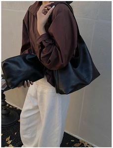 Close-up of black leather tote bag with fashion lettering and matching small pouch