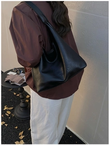 Close-up of black leather tote bag with FASHION & LEATHER embossed detail on shoulder