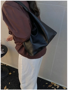 Detail of wide shoulder strap and matte black leather texture on a tote bag