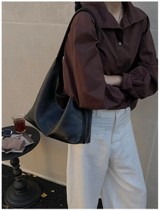 Detail of a large black glossy leather tote bag showing fashion print and spacious interior