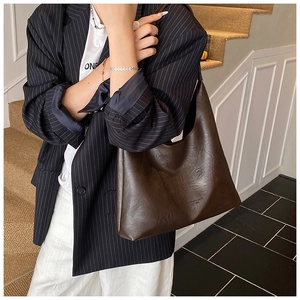 Detail of dark brown leather tote bag showing large capacity and smooth texture