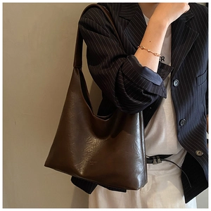 Detail view of large dark brown retro hobo bag in soft oil wax leather texture on shoulder