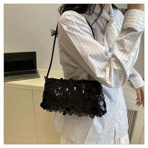 Detail of a chic black sequin shoulder bag shown on model with leather strap and chain