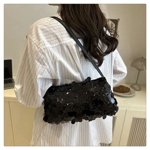 Dettaglio della borsa baguette nera con grandi paillettes tonde e finitura lucida