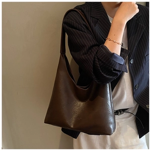 Detail of deep brown leather hobo bag with vintage texture and subtle logo embossing