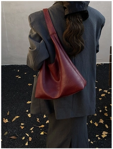Outdoor shot of dark red tote bag on model shoulder with grey blazer and fallen leaves