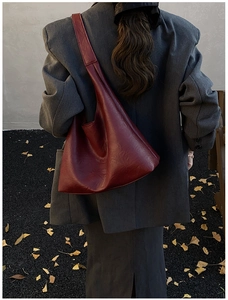 Macro view of wide strap detail on dark red hobo bag against autumn ginkgo leaves