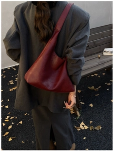 Detail of dark red leather tote bag with embossed fashion text in an autumn setting