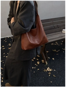 Close-up of vintage brown leather tote bag with embossed fashion text in autumn setting