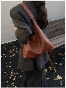 Detailed close-up of brown pebbled leather texture on a large capacity tote shoulder bag