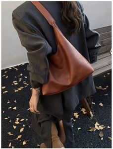 Close-up of vintage brown leather tote bag showing textured finish and embossed text