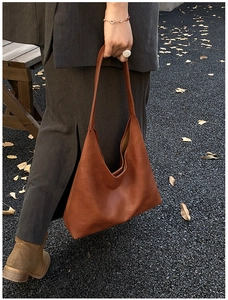 Brown leather tote bag styled with gray suit and autumn leaves in a street view