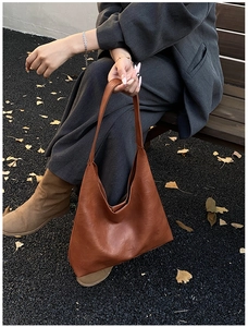 Detailed close-up of brown leather hobo bag with embossed fashion text and texture