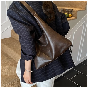 Detailed side view of a large vintage brown tote bag showing supple oil wax leather texture