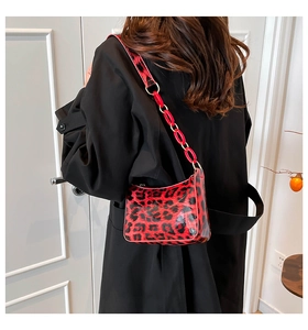 Detail of red and black leopard print hobo bag with red acrylic chain on black coat