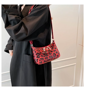 Detail of red leopard print glossy underarm bag with gold buckles and shoulder strap