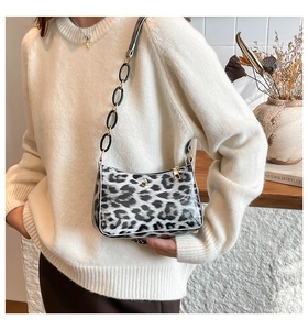 Detail of grey leopard print baguette bag with metal chain strap and sleek zipper