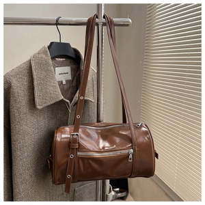 Detail of vintage brown cylinder bag showing shiny PU leather texture and adjustable strap