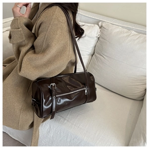 Detail of dark brown leather pillow bag with silver buckles on a casual shoulder strap