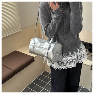 Silver cylindrical pillow bag worn by a model in a casual urban fashion styling
