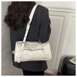 Detail of off-white glossy leather bowling bag with silver zipper pocket and adjustable strap