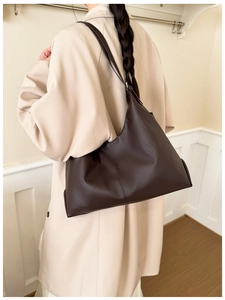 Deep brown matte leather tote bag with vertical stitching shown on model shoulder