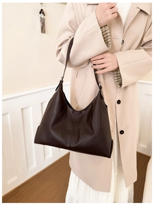 Close-up of deep brown leather tote bag with vertical stitching and adjustable strap