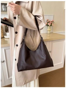 Deep brown matte leather hobo bag styled with a beige coat in a modern home setting