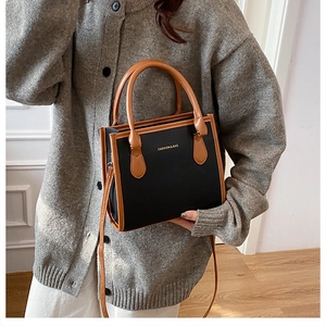 Detail of fashion tote bag with brown leather trim and adjustable crossbody strap