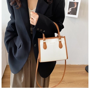 Detail of white and brown crossbody bag with litchi texture on a fashion model