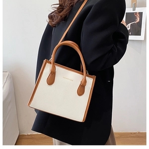 Close-up of a white and brown bicolor tote bag with high-quality lychee grain texture