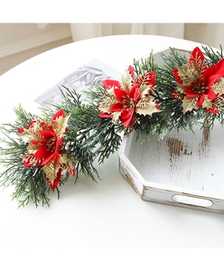 Detail of Christmas garland with red poinsettia flowers and gold leaves on white table