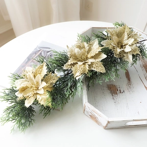 Christmas wreath with artificial green pine needles and three golden glitter poinsettias