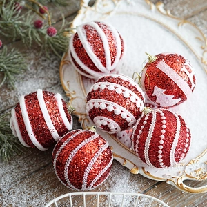 Set of 6 red glitter Christmas balls with white flocked patterns on a snowy wooden background